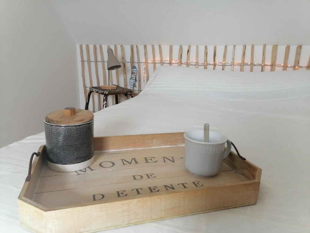 a wooden tray with two cups on a bed at Aux Caboteurs in Arzal