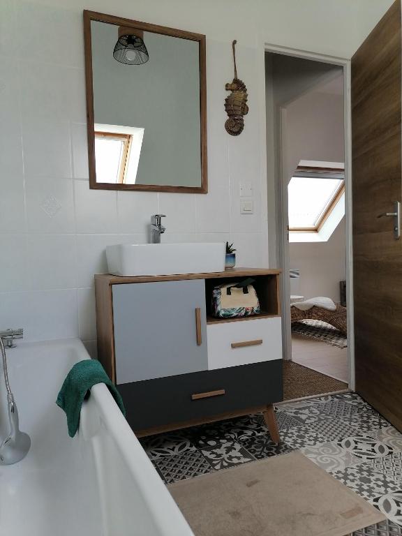 a bathroom with a sink and a tub and a mirror at Aux Caboteurs in Arzal
