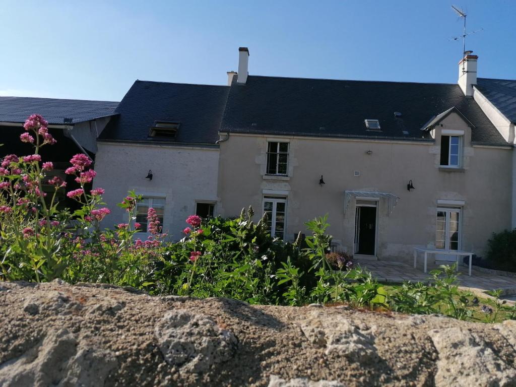 une vieille maison avec des fleurs devant elle dans l'établissement Le gîte d' Alice, à La Chapelle-Saint-Martin-en-Plaine