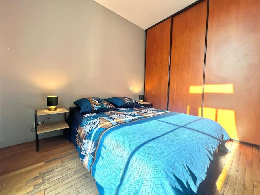 a bedroom with a large bed and a wooden wall at Le Calypso, superbe T3+Parking proche du centre in Poitiers
