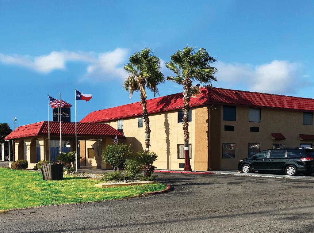 a hotel with palm trees in front of a building at Baymont by Wyndham Del Rio in Del Rio