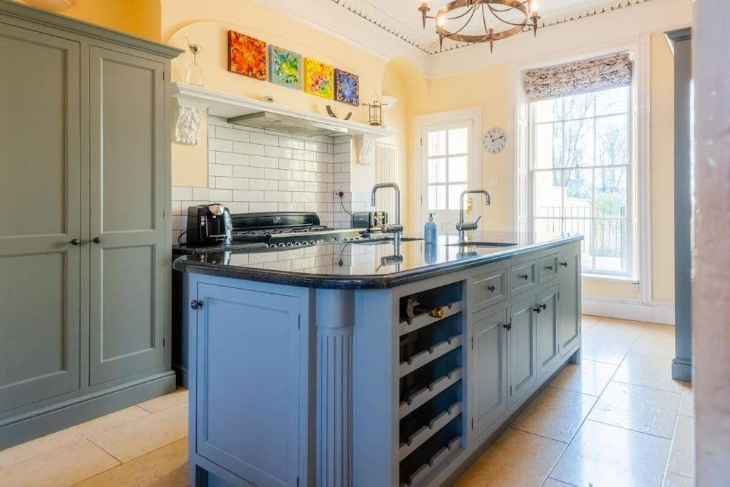 a kitchen with a blue island with wine racks at Large Central 5 Bed House with Stunning Gardens! in Cheltenham