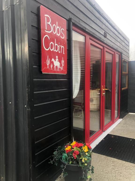 een bord aan de zijkant van een gebouw met bloemen bij Bob’s Cabin in Galway