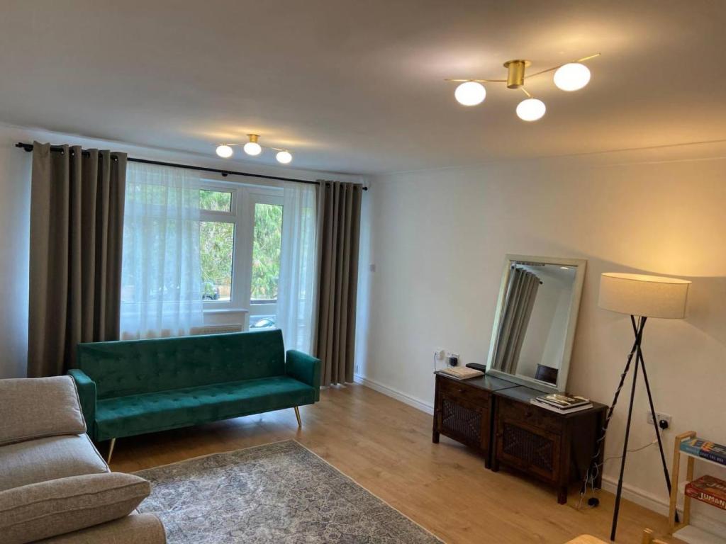 a living room with a green couch and a mirror at Spacious - 3 double beds - Wi-Fi - Central Northwood - Free Parking in Northwood