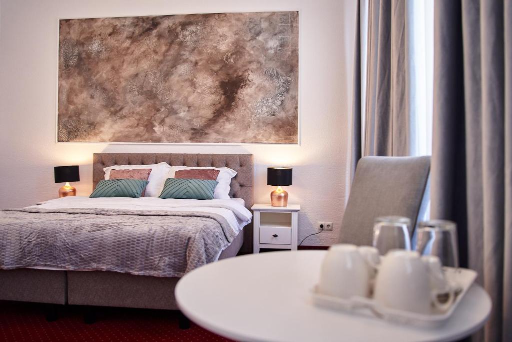 a bedroom with a bed and a table and a painting at Charma Residence in Sibiu