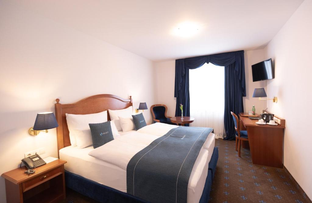 Cette chambre comprend un grand lit et un bureau. dans l'établissement Select Hotel Prinz Eugen Wien, à Vienne