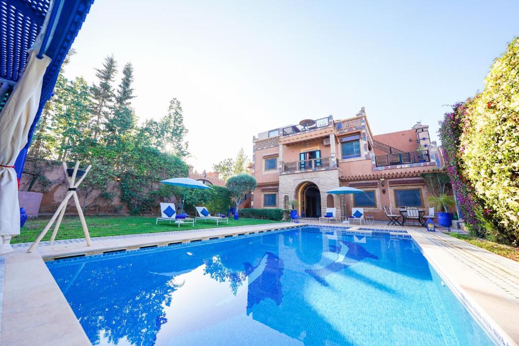 a swimming pool in front of a house at Villa Timskrine - Panoramic Mountains View in Marrakech