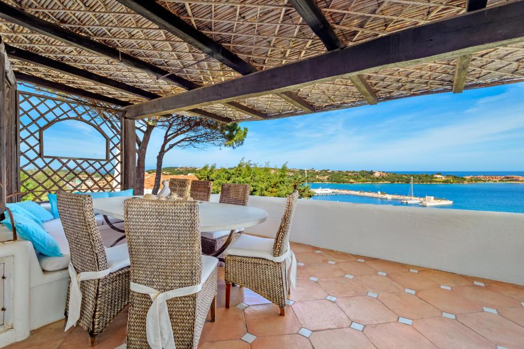 une terrasse avec une table et des chaises et l'océan dans l'établissement Terrazza sul mare a Porto Cervo, à Porto Cervo