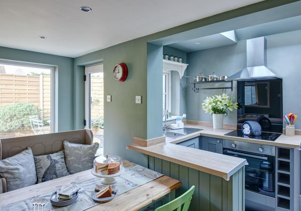 a kitchen with green walls and a wooden table at Rose Cottage - North Elmham in North Elmham