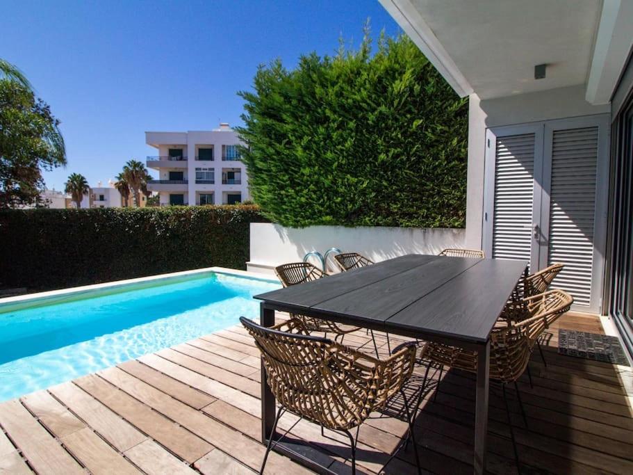 a patio with a table and chairs next to a pool at Fun House - Privat Heated Pool & Snooker & BBQ & Privacy & Albufeira in Albufeira