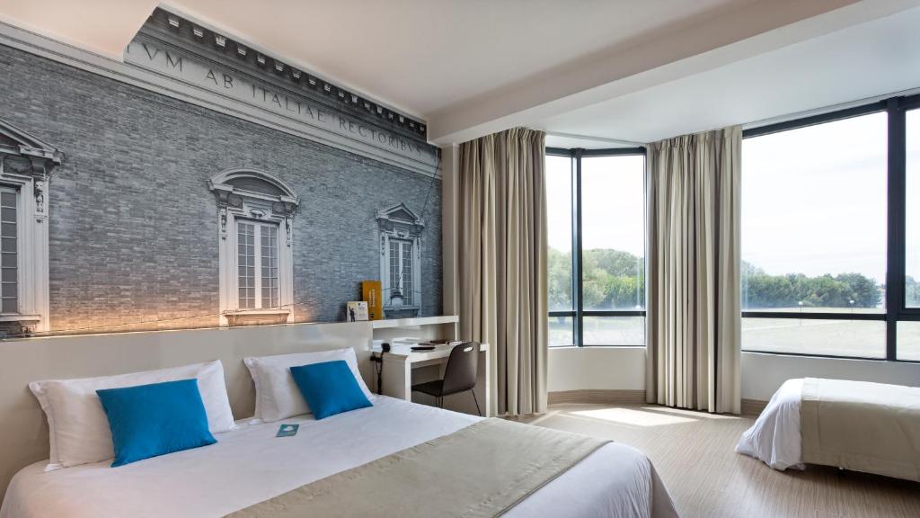 - une chambre avec un grand lit et des oreillers bleus dans l'établissement B&B Hotel Ravenna, à Ravenne