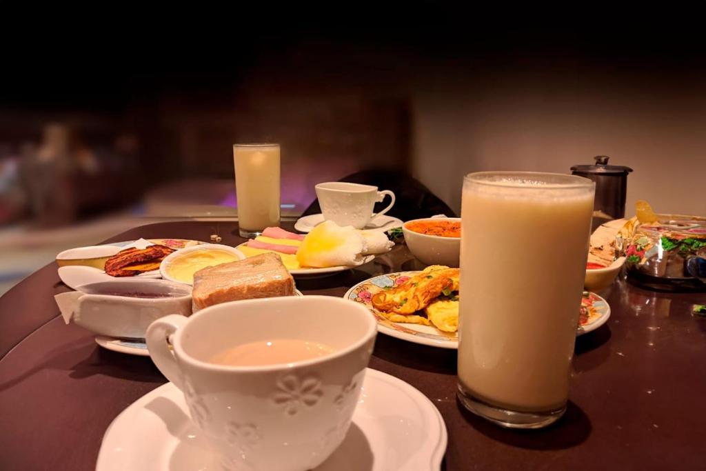 una mesa con platos de comida y un vaso de leche en Pousada Ponta Negra, en Manaus