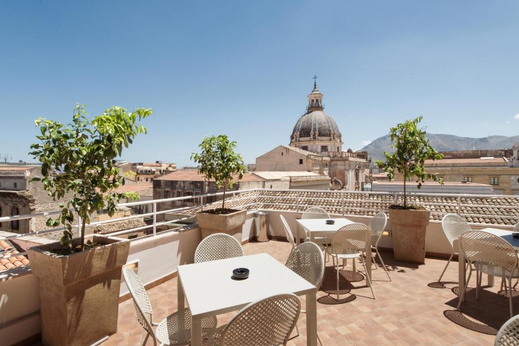 un patio con tavoli e sedie sul tetto di un edificio di B&B Hotel Palermo Quattro Canti a Palermo