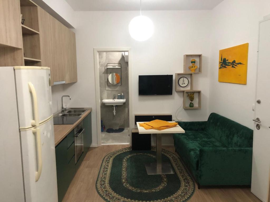 een woonkamer met een groene bank en een keuken bij J & A in Tirana