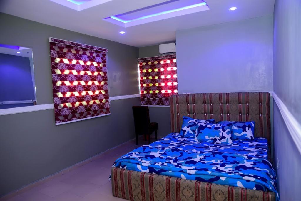 Mena's Home & Apartment في Ughelli: غرفة نوم بسرير وتلفزيون بشاشة مسطحة