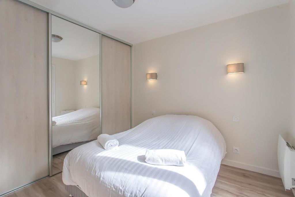 ein Schlafzimmer mit einem weißen Bett und einem großen Spiegel in der Unterkunft Le Petit Parfait in Grenoble