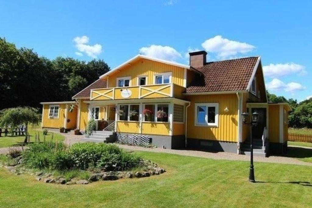 ein großes gelbes Haus mit einem Hof in der Unterkunft Ferienwohnung Småland ausserhalb Älmhult in Diö