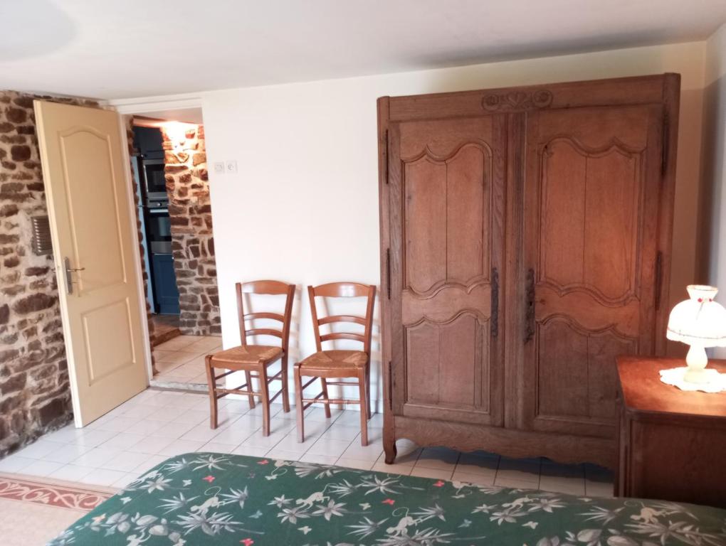 a bedroom with a door and chairs in a room at Entre forêts et prairies in Le Cercueil
