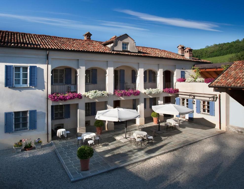 una vista exterior de un edificio con mesas y sombrillas en Marcarini Agriturismo, en Neviglie