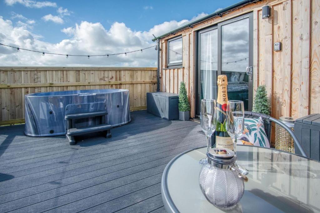 eine Terrasse mit einem Tisch und einer Flasche Champagner in der Unterkunft Willows Rest - 1 Bed Shepherds Hut - Pentlepoir in Saundersfoot