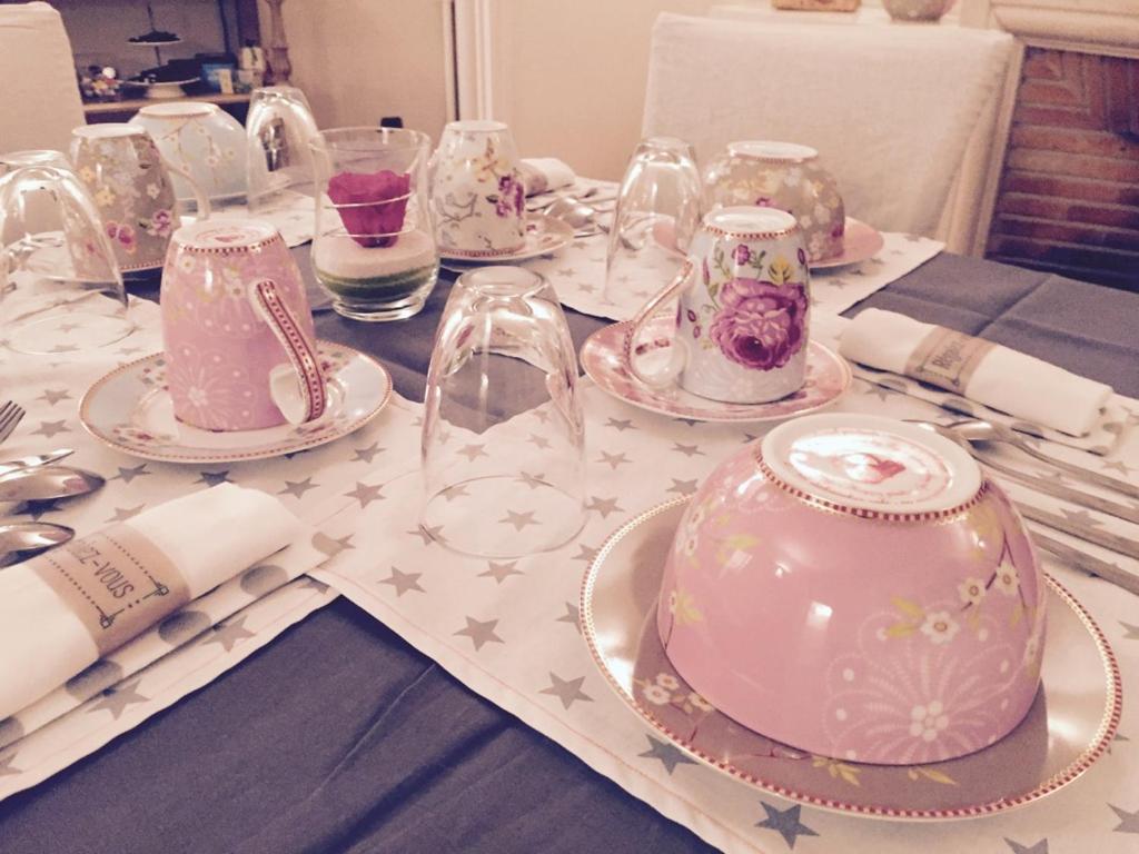 a table topped with pink and white dishes and glasses at La pierre d'O in Longpré-les-Corps-Saints