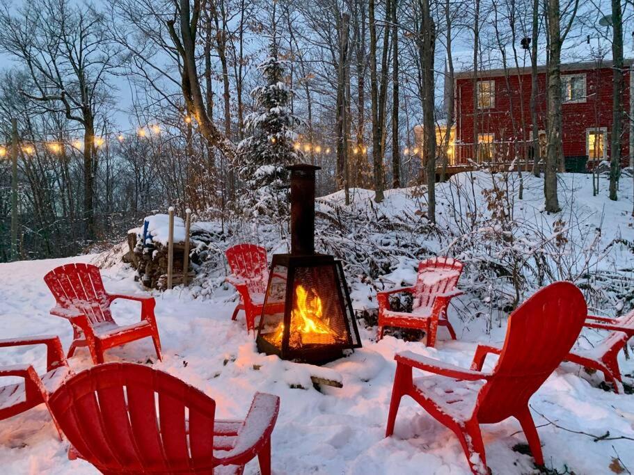 Eine Gruppe Stühle im Schnee mit einem Kamin in der Unterkunft Nature retreat with HOT TUB and lake access & watercraft in Saint Adolphe D'Howard