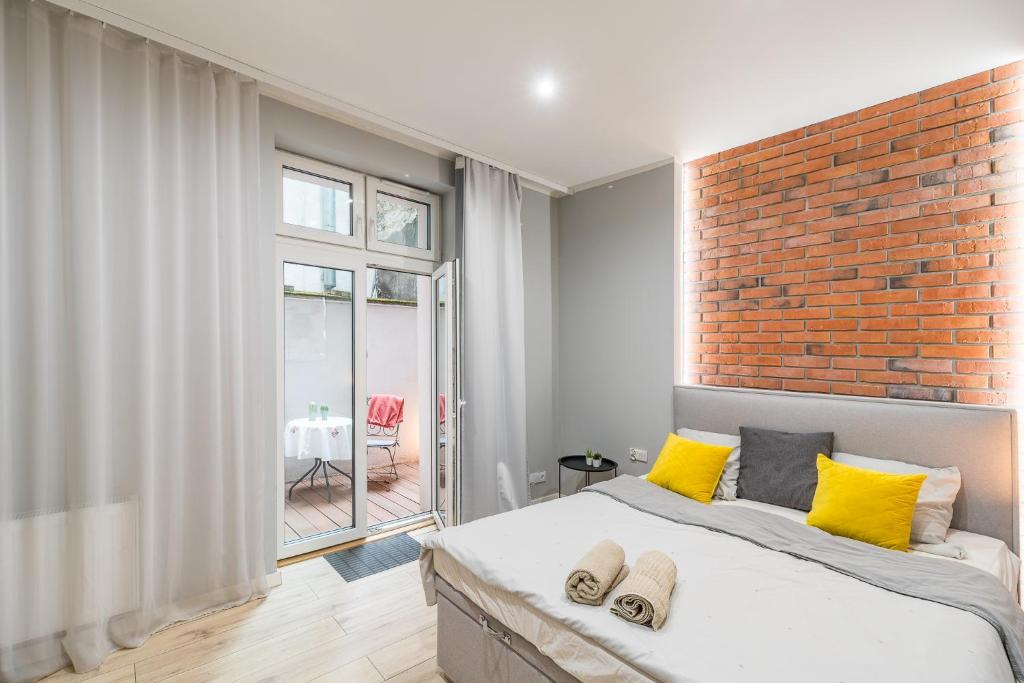 um quarto com uma parede de tijolos e uma cama com almofadas amarelas em Starowiślna Apartment - Balcony, Top Location, Tram & Train Nearby - by Rentujemy em Cracóvia