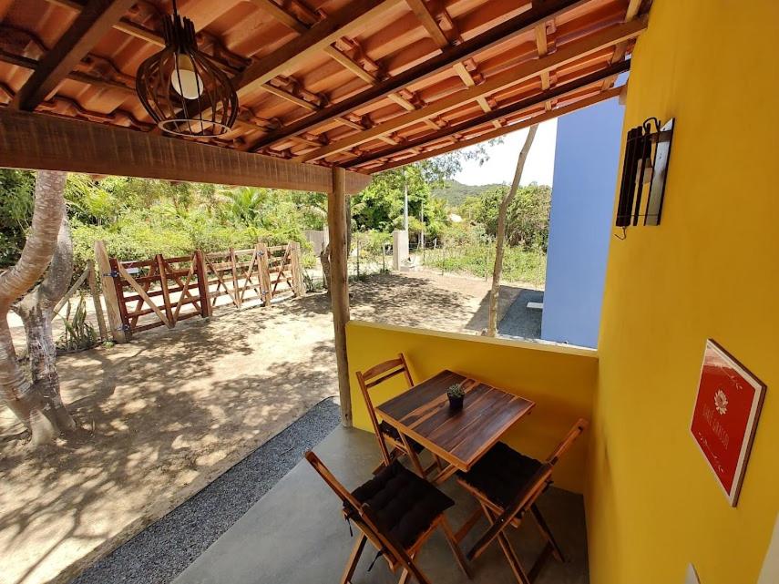 a wooden table and chairs in a room with a patio at Flor e Luz Chalés in Vale do Capao