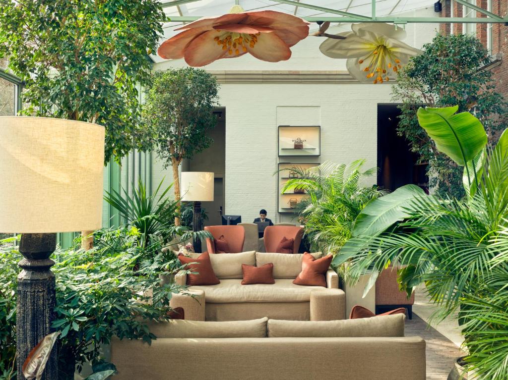 ein Wohnzimmer mit Sofas und Pflanzen in der Unterkunft Botanic Sanctuary Antwerp - The Leading Hotels of the World in Antwerpen