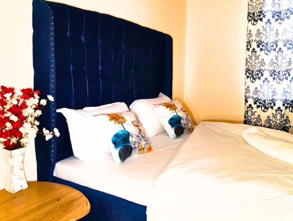 a bed with a blue headboard and three pillows at The Chocolate House in Athi River