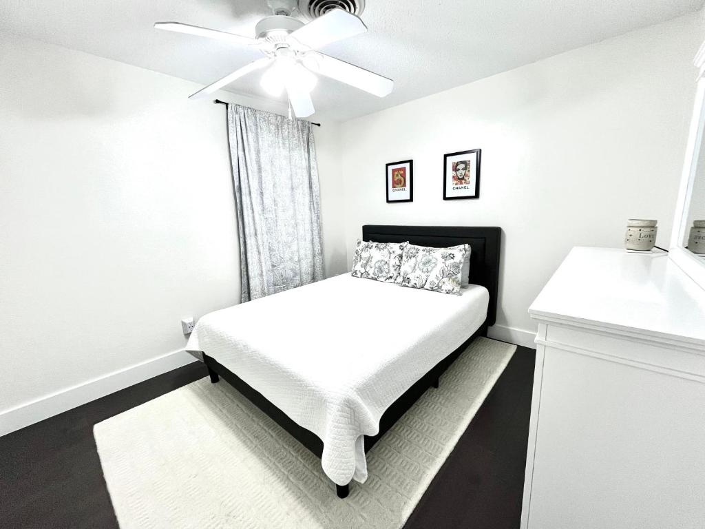 - une chambre blanche avec un lit et un ventilateur de plafond dans l'établissement Sunshine State of Mind House, à Jensen Beach