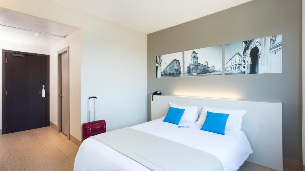 1 dormitorio con 1 cama blanca y 1 maleta roja en B&B Hotel Ferrara en Ferrara