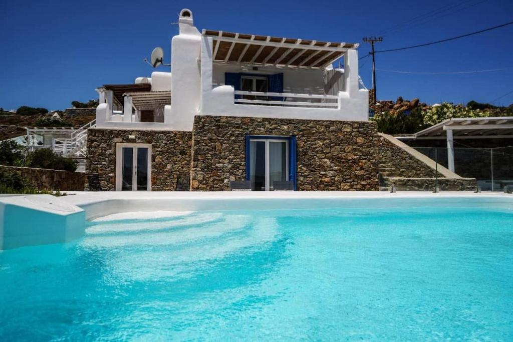 a villa with a swimming pool in front of a house at Mykonian Exclusive 3Bd Villa with Private Pool in Panormos Mykonos