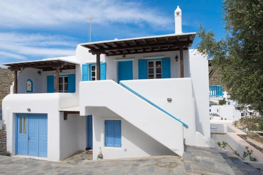 una pequeña casa blanca con una puerta azul y una torre blanca en Mykonos Elegance 2-Bedroom Escape in Psarou, en Platis Gialos