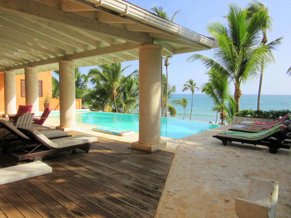 a resort with a pool and chairs and the ocean at Villa Los Gorgones in Las Galeras