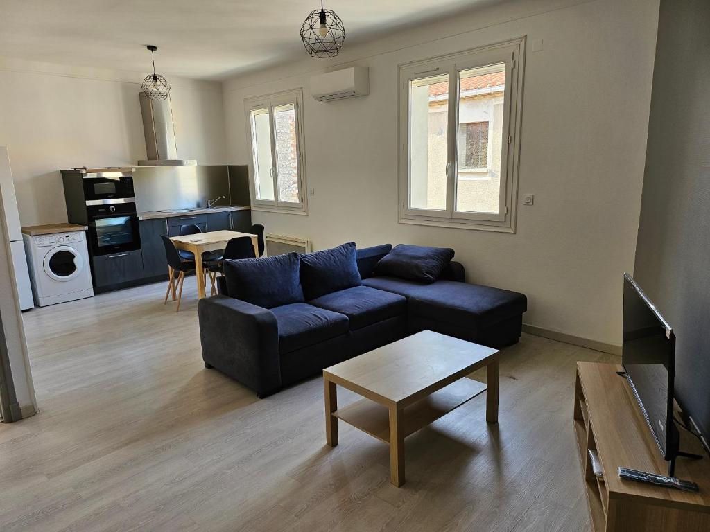 un salon avec un canapé bleu et une cuisine dans l'établissement Appartement proche de toutes commodités, à Rivesaltes