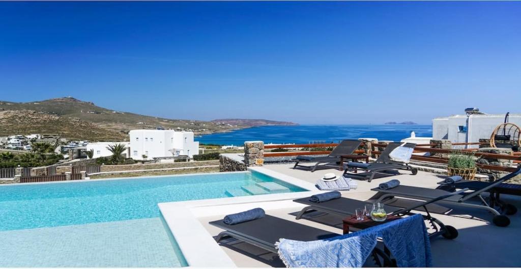 a pool with lounge chairs and a view of the ocean at Luxury White Oasis Villa w Private Pool in Mikonos in Kalafatis