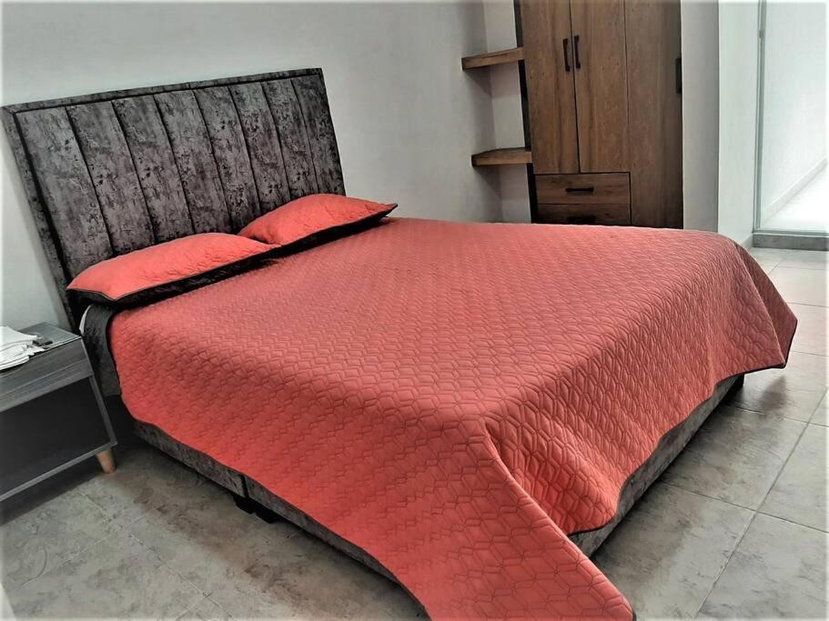 uma cama vermelha com almofadas vermelhas num quarto em Apartaestudios White And Grey em Popayán