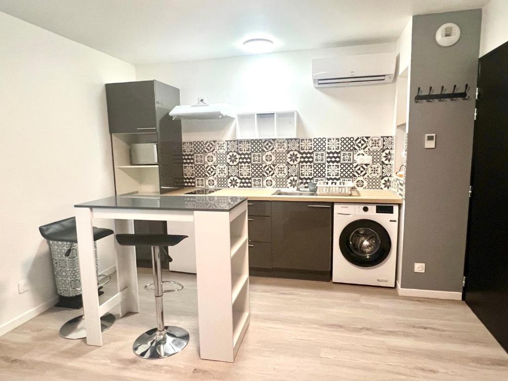 uma cozinha com uma mesa e uma máquina de lavar roupa em Résidence ATIPYC em Marssac-sur-Tarn