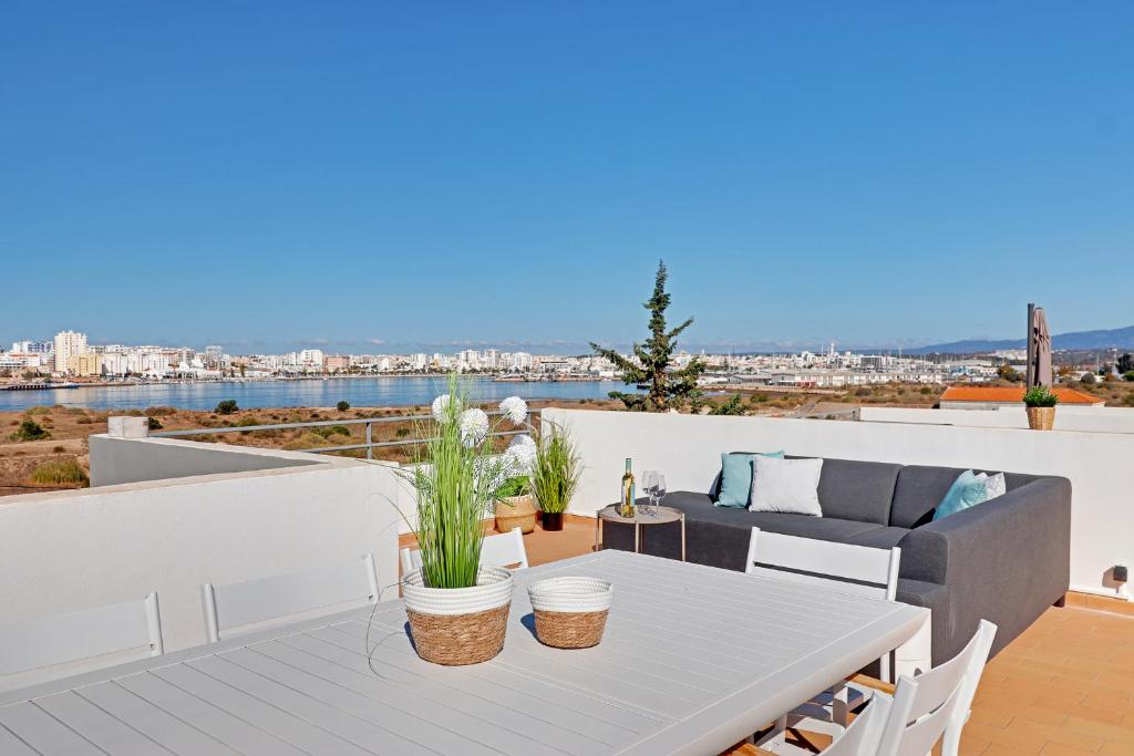 a patio with a table and a couch on a deck at Casa Ferraguido by Portucasa in Ferragudo