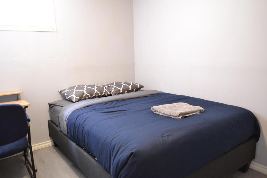 1 dormitorio con 1 cama con manta azul y almohadas en Private Bedroom on the main floor with shared washroom - Erin Woods en Calgary