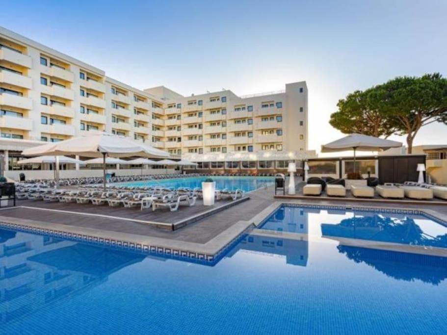 a hotel with a swimming pool with chairs and umbrellas at Albufeira Sol Villas V - Pool and Garden & Gym & SPA in Albufeira