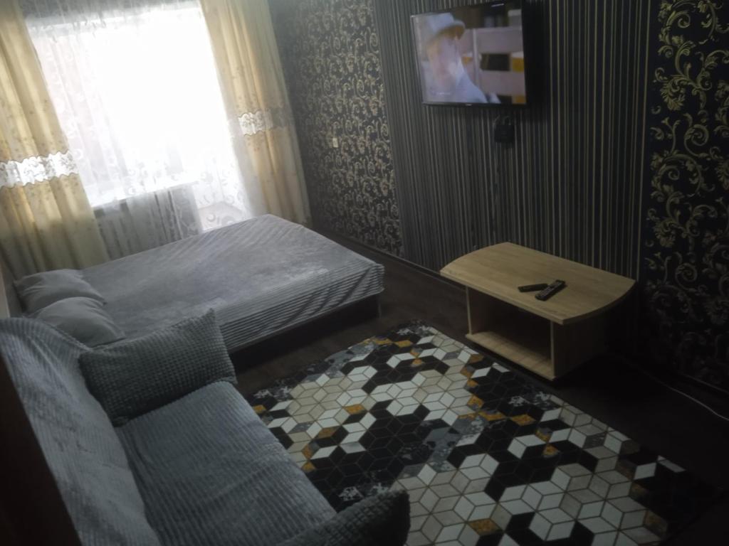 ein kleines Schlafzimmer mit einem Bett, einem Tisch und Stühlen in der Unterkunft Апартаменты посуточно по Ауэзова in Öskemen