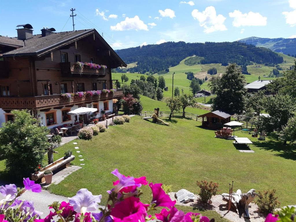 a building on a hill with a green field and flowers at Schranbachhof in Maria Alm am Steinernen Meer