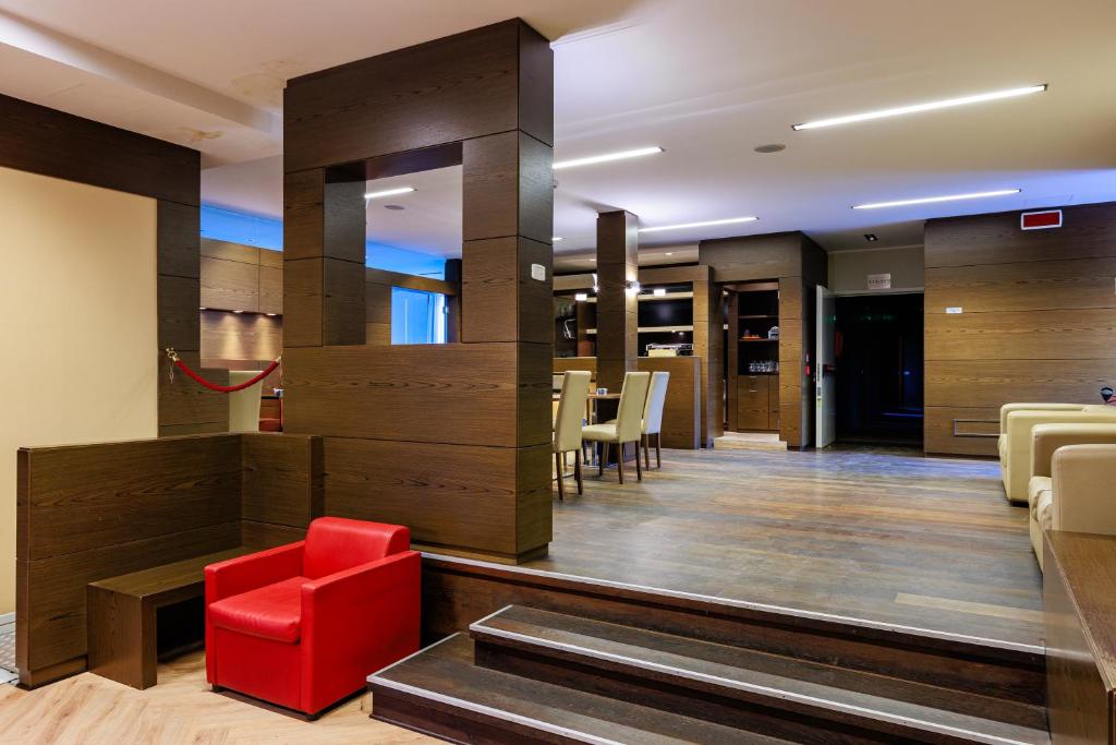 a lobby with a red chair in a room at Hotel Villa Delle Rose - Malpensa in Oleggio