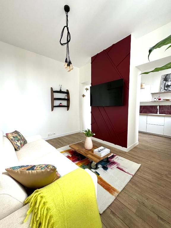 - un salon avec un canapé et un mur rouge dans l'établissement Chez Alexia et Vincent, à Lille