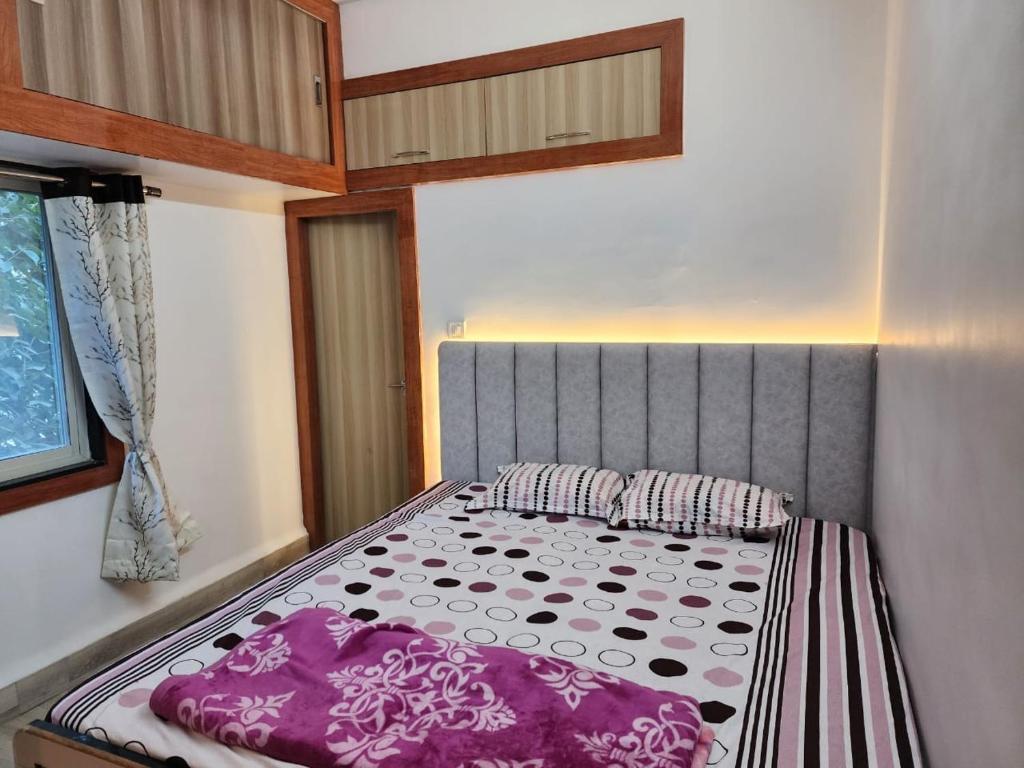 a small bedroom with a bed with purple pillows at 2BHK fully furnished apartment in Indore