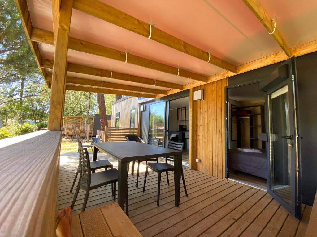 une terrasse en bois avec une table et des chaises dessus dans l'établissement CAMPING LES OURMES, à Hourtin