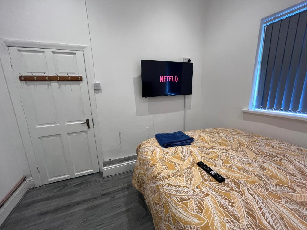 a bedroom with a bed and a tv on the wall at Snugly Studio Flat near Talbot Pub in Birmingham