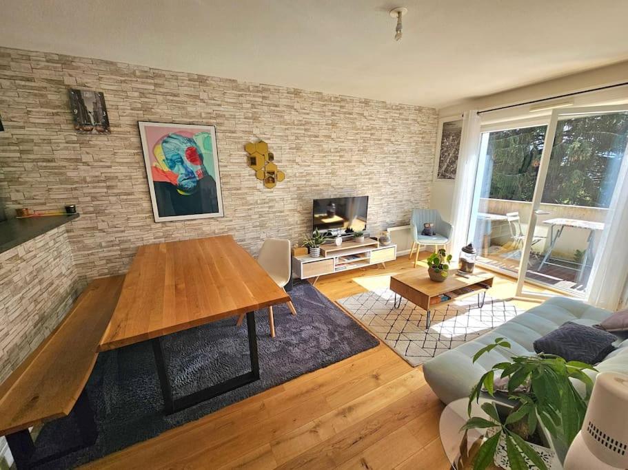 a living room with a table and a brick wall at L'hippique - Parking - vue Pyrénées - Balcon in Pau